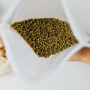 High angle view of mung beans in a white bag with ginger in background.